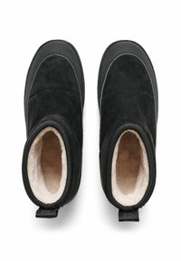 Svarta ankelboots i mocka med mjukt, ljust fleecefoder. Har en rundad design med dragflikar bak.