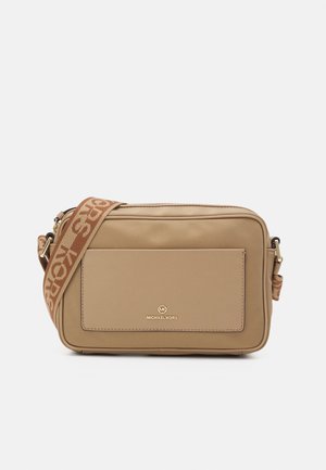 Sac bandoulière beige avec une texture lisse, arborant un logo doré à l'avant et une sangle marron à motif. Forme rectangulaire avec une fermeture éclair.
