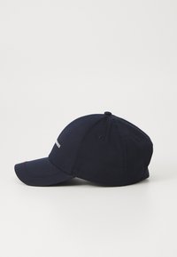 Marineblå baseball cap lavet af bomuld med en buet skygge, broderet logo på forsiden og justerbar rem bagpå.