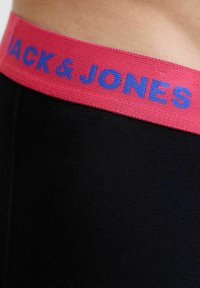 Črne tkanine oblačila z širokim rožnatim pasom, na katerem je modri napis "JACK & JONES" na pasu osebe.