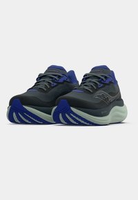 Sapatilhas de corrida cinzentas e azuis com um cabedal texturizado, sola acolchoada e um padrão de sola distinto. Apresenta o logótipo na lateral e cordões.