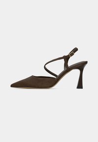 Escarpin slingback en daim marron avec un bout pointu, des lanières étroites et un talon aiguilles. Comprend un détail de boucle ajustable en métal doré.