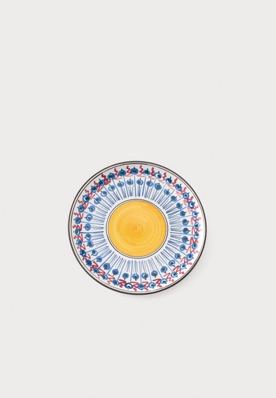 Assiette en céramique avec un centre jaune et un motif circulaire décoratif bleu et rouge autour du bord sur un fond clair.