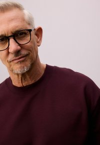 Bordeaux crewneck sweatshirt lavet af blødt stof, med en glat tekstur og minimale sømdetaljer, båret af en mand med briller.