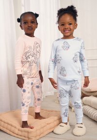 Du vaikai dėvi derančius pižamus. Vienas vilki rožinį viršų su snaigių raštais, kitas – šviesiai mėlyną su personažų piešinėliais.