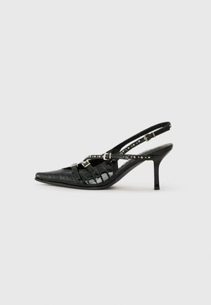 Tacchi alti slingback neri con punta affilata, texture coccodrillo, cinturini regolabili e borchie argentate lungo i dettagli delle cinghie.