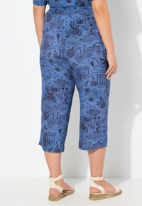 Blauwe capri-broeken met een gedrukt ontwerp dat architectonische en natuurlijke elementen bevat. Gemaakt van lichtgewicht stof, enkel-lang met een relaxte pasvorm.
