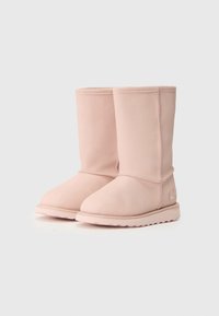 Pár mid-calf ružových semišových čižiem so zaoblenými špičkami a plochými gumovými podrážkami, umiestnených vedľa seba na jednofarebnom pozadí.