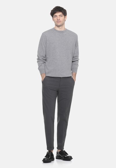 Maglione grigio realizzato in tessuto lavorato a maglia, abbinato a pantaloni grigi scuri su misura e scarpe stringate nere. Design semplice con scollatura a girocollo.