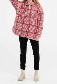 Vaaleanpunavalkoruudullinen flanellipaita, jossa on kaksi rintataskua ja napit, yhdistetty mustiin farkkuihin ja beigenvärisiin nilkkureihin.