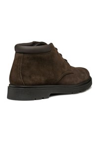 Stivaletti alla caviglia in suede marrone con punta tonda, lacci minimali e suola in gomma nera. Il collare contrasta con una finitura in materiale liscio.