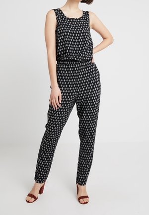 Černobílý overal s vzorem, bez rukávů a s elastickým pasem, s kónickými nohavicemi a výstřihem do oblouku.