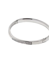 Srebrna bransoletka w kształcie bangle z gładkim, zaokrąglonym wzorem, ozdobiona rzędem przezroczystych kryształków po jednej stronie. Posiada zapięcie na zawiasy, co ułatwia zakładanie.