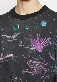 Pull sombre avec broderies colorées sur le thème céleste et océanique, incluant des étoiles, la lune, une planète, un oiseau et des créatures marines.