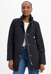Schwarze wasserdichte Jacke mit hohem Kragen, Frontreißverschluss, Druckknöpfen und seitlichen Taschen. Glatte Textur und lässiges Design.