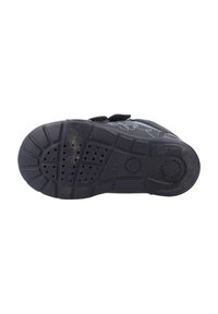 Semelle de chaussure noire pour enfant en bas âge avec grip texturé et marquage circulaire "Softly Cushion" au niveau du talon.
