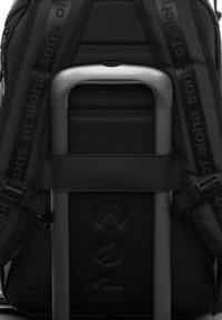 Sac à dos noir avec une texture rembourrée, doté d'une poignée métallique, de bretelles réglables et de détails de logo en relief, vu de l'arrière.