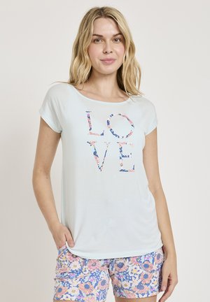 Lyseblå T-shirt med korte ærmer med ordet "KÆRLIGHED" i blomsterfyldte bogstaver. Sammen med multikolorede blomsterbukser med en pastelpalette.