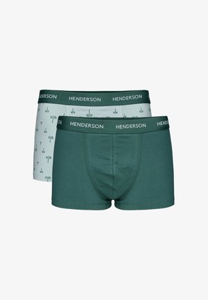 Oberkörperfreier Mann mit kurzem braunem Haar, trägt dunkelgrüne Boxer-Shorts mit "Henderson"-Bund, steht vor einem einfarbigen hellen Hintergrund.