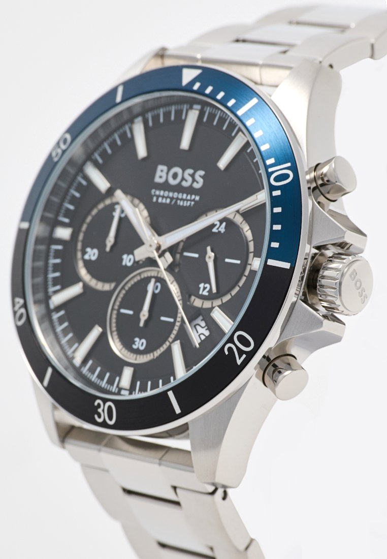 Reloj cronógrafo de acero inoxidable con esfera negra, bisel azul y acentos plateados. Incluye tres subesferas y una pulsera pulida.