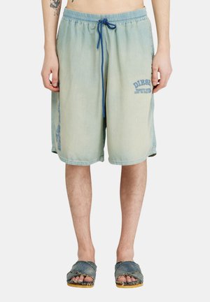 Short en jean bleu clair avec taille élastique et cordon bleu, porté par une personne visible de la taille aux pieds dans des sandales en jean effilochées.