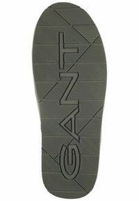 Zwarte rubberen schoenzool met gegroefde textuur en verhoogd "GANT" logo. Bevat hoekige patronen en horizontale lijnen voor grip.