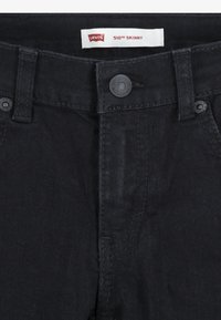 Black denim jeans with a skinny cut, featuring a button closure, five pockets, and a contrasting Levi's logo tag on the waistband.