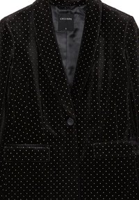 Blazer in velluto nero con pois dorati, rever a punta, chiusura con un solo bottone e due tasche frontali. Etichetta visibile all'interno del colletto.