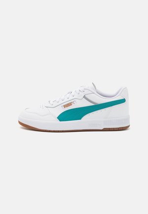 Biały sneaker marki Puma z turkusowym paskiem, białymi sznurowadłami i gumową podeszwą, pokazany z boku na jednolitym tle.