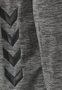 Tissu gris texturé avec quatre motifs de chevrons noirs pointant vers le bas, disposés verticalement sur le côté gauche.