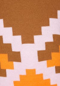 Stickad tyg med ett pixelmönster i nyanser av brunt, rosa och orange, som visar en strukturerad yta och blandade färger.