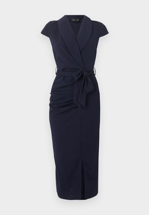 Ermeløs midikjole i marineblå med sjalkrave, rynking på siden, splitt foran og knyttebånd i midjen.