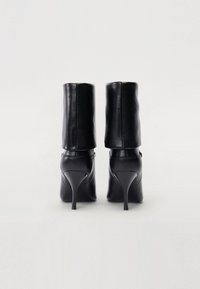 Bottes à talons hauts en cuir noir, avec une texture lisse, un bout arrondi et une tige cylindrique atteignant le mollet.