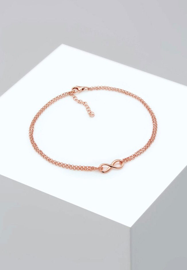 Armband i roséguld med kedjedesign som har en central oändlighetssymbol. Slät yta och en krabba-lås med en förlängningskedja.