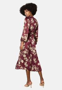 Burgunderfarbenes Blumen-Midi-Kleid mit langen Ärmeln, strukturiertem Stoff, botanischen Drucken in Creme und einer taillierten Silhouette mit schwingendem Rock.
