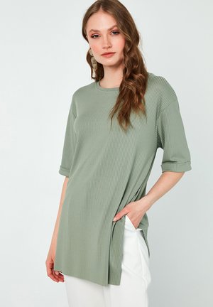 Light green ribbed top with short sleeves, crew neckline, and side slits. Designed with a relaxed fit and smooth texture.