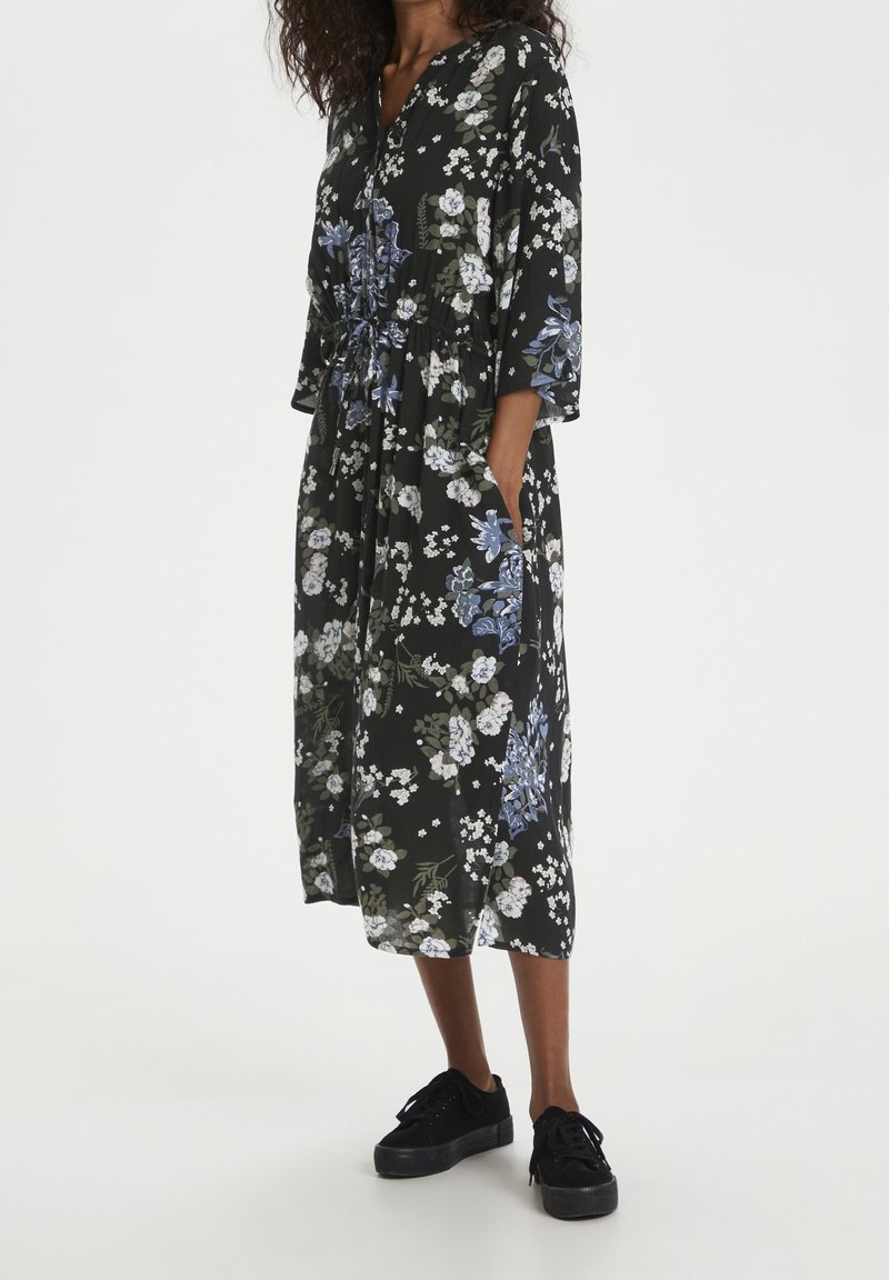 Robe midi fleurie en tissu noir, ornée d'un mélange de fleurs bleues et blanches, avec un décolleté en V, des manches trois-quarts et des poches latérales.