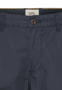 Marineblauwe broek van lichtgewicht stof met een knoopsluiting, riemlussen en gele accentstiksels langs de tailleband.