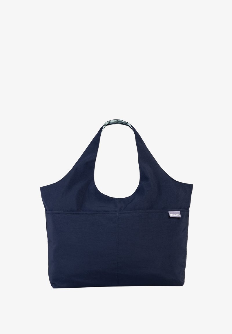 Navy fabric tote bag with a large, curved handle. Features a front pocket and a patterned lining. Sturdy, simple design.