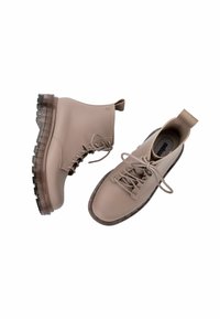 Botas de tobillo impermeables beige con una textura suave, punta redonda, cordones en la parte delantera y suelas gruesas transparentes. Asa para facilitar el calzado.