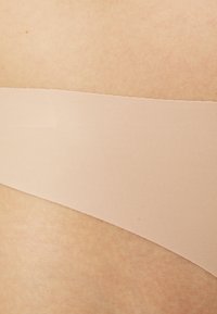 Nagi taśma klejąca o gładkiej fakturze, szerokości około 5 cm, przyklejona do skóry, z miękkim matowym wykończeniem bez wzorów.