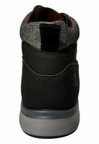 Zapatilla negra con parte superior texturizada, cuello con patrón y suela gris. Presenta un pequeño detalle de logo en el talón y una pestaña de agarre para facilitar su uso.