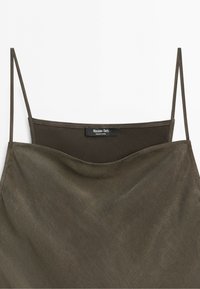 Slipklänning i olivgrönt med tunna axelband och en etikett med texten Massimo Dutti made in China vid bakre halsringningen.