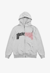 Grijze hoodie met rits en een capuchon met trekkoord. Voorzien van de tekst "Waste" in zwarte en gestileerde rode letters aan de voorkant. Heeft twee zakken aan de voorkant.