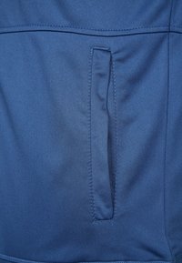 Blue fabric with a smooth texture features a vertical pocket stitched into the design, showcasing clean lines and minimalistic style.