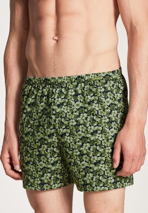 Bloemige zwembroek in donkergroen met lichtgroene bloemen. Elastische tailleband, lichtgewicht stof en een relaxte pasvorm.