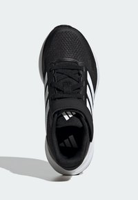Scarpa sportiva nera con parte superiore testurizzata, dettagli bianco a strisce e suola ammortizzata. Presenta una tradizionale allacciatura e un tassello rinforzato sul tallone.