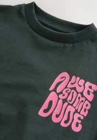 Dunkelgrünes Sweatshirt mit einem großen, lustigen, pinken Grafiktext-Design, das "AWESOME DUDE" liest. Bündchen am Hals und weicher Stoff.