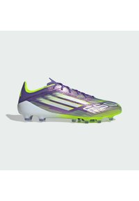 Paarse voetbalschoen met een gradient ontwerp, voorzien van een gestructureerde bovenkant, groene accenten en een gemodelleerde zool met meerdere noppen.