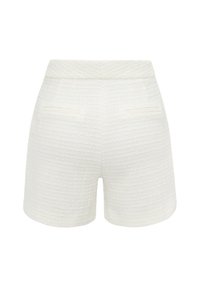 Valkoiset teksturoidut shortsit, joissa on korkea vyötärö, kaksi etutaskua ja suoralinjainen leikkaus. Suunniteltu koko vaatteessa käytetyn kudontakuvion kanssa.
